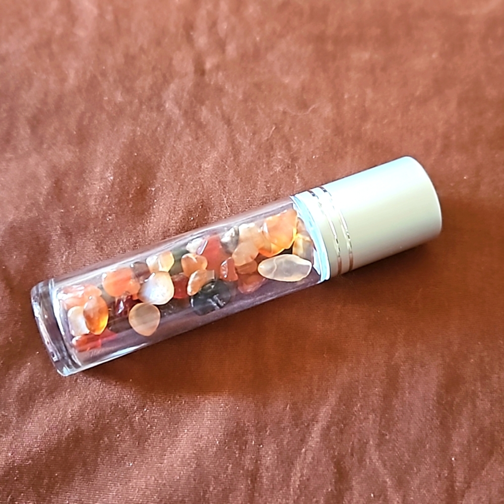 Empty glass roll on bottle with Red Agate chips inside